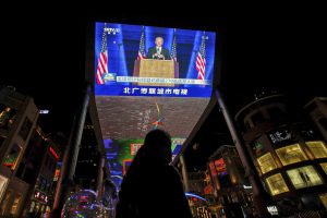 FILE - In this Nov. 8, 2020, file photo, a woman sells balloons near a giant TV screen broadcasting a news of U.S. President-elect Joe Biden delivers his speech, at a shopping mall in Beijing. (AP Photo/Andy Wong, File)