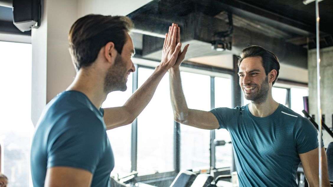 Mann på treningssenter som gir seg selv high five i speilet