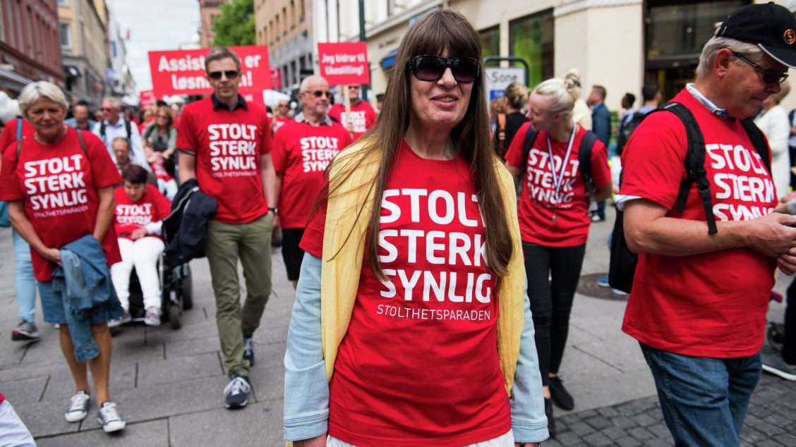 Bilde fra stolthetsparaden, viser mennesker som går i tog, alle har på røde t-skjorter der det står "stolt, sterk, synlig".